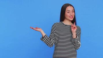 Young woman showing thumbs up and pointing at left on blank space place for your advertisement logo video