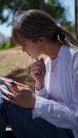 Female professional journaling in sunlit urban park, documenting creative ideas amid green surroundings, experiencing serene outdoor workspace video