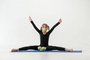 sano comiendo, verde,, manzanas pequeño niña en yoga ropa es en el aptitud estera foto