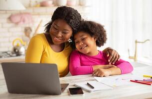 Happy African American Mom And Her Cute Little Daughter Using Laptop Together In Kitchen, Black Family Having Fun At Home, Embracing And Watching Cartoons Or Kids Development Videos Online, Free Space photo